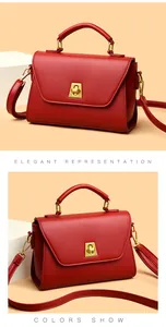 Détail du sac en cuir rouge montrant le fermoir trapèze doré et la texture fine