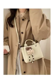 Detail of beige lychee grain bucket bag with detachable strap and mushroom plush charm