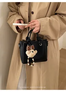 Minimalist black lychee texture bucket bag with cute plush bear charm and metallic hardware
