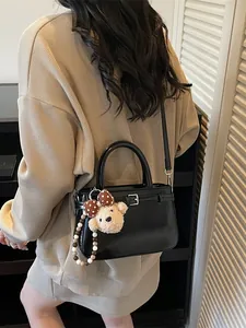 Black patent leather bucket bag with a cute plush bear charm and silver hardware accents