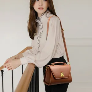 Minimalistische braune Leder-Handtasche mit goldener Metall-Drehschließe und Tragegriff