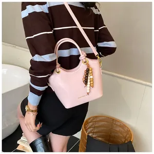 Detalle de bolso tipo cubo rosa con borla de cuentas y logo para mujer