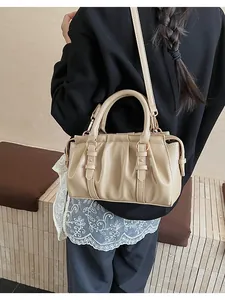 Detailansicht der beigen Plissee-Tasche mit goldenen Beschlägen am Schultergurt
