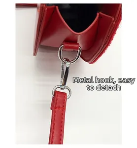 Detail of red leather crossbody bag featuring durable silver metal hooks and fine stitching