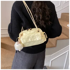 Detalle del bolso de charol acolchado amarillo claro con cadena dorada y pompón blanco