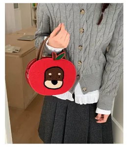 Detail of red apple-shaped plush handbag with cute puppy embroidery and brown handles