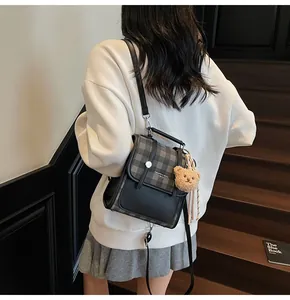 Detailed back view of a mini plaid backpack with a plush bear charm on a model
