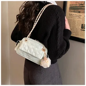 Bolso acolchado verde menta con cadena dorada y pompón mostrado en una modelo
