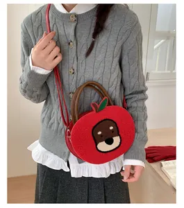 Detail showing plush apple-shaped bag with cute puppy embroidery and brown top handles