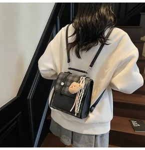 Detail of checkered tote bag with silver buckle, bear charm and detachable strap