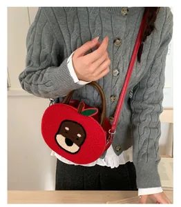 Detail of red apple-shaped plush crossbody bag featuring a cute dog patch and green leaf