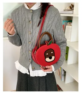 Detail of red apple-shaped faux fur handbag with cute cartoon embroidery and top handle