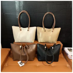 Minimalist large leather tote bags in four colors displayed on a brown leather bench