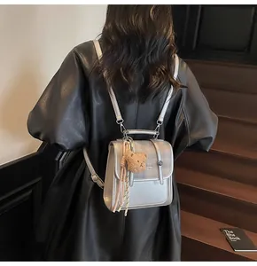 Silver textured backpack with plaid flap and bear charm shown on a leather jacket model