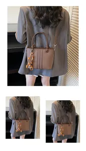 Detail of a brown bucket bag with decorative wooden bead tassel and vertical embossed lines