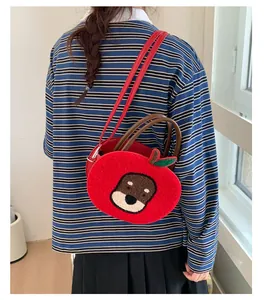 Detail of red apple-shaped crossbody bag featuring cute cartoon puppy embroidery and strap