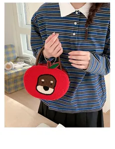 Detail of red apple-shaped plush bag with dog embroidery and silver chain handle