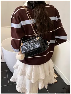 Detalle del bolso acolchado con cadena dorada y colgante de oveja de felpa blanca
