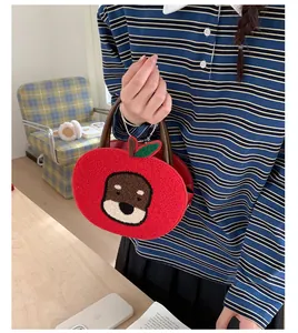 Detail of red plush apple-shaped bag with puppy embroidery and metal chain strap