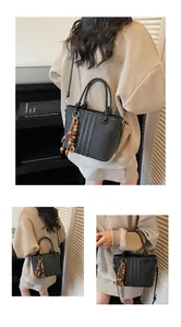 Detail of black bucket bag featuring white vertical stitching and retro wooden bead pendant