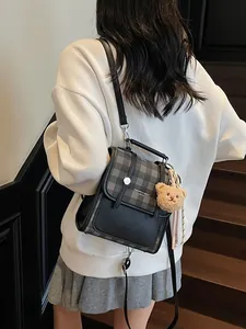 Plaid patchwork convertible mini backpack with teddy bear charm shown on a model