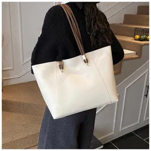 Detailed view of the large white leather tote bag with dark brown shoulder straps on a model