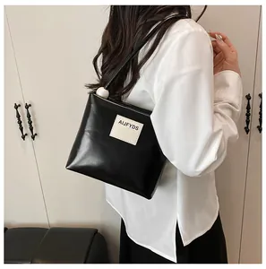 Dettaglio borsa a secchiello in pelle PU nera con perla bianca e toppa logo
