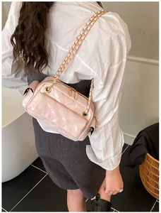 Detalle de bolso baguette rosa acolchado con cadena dorada visto desde un ángulo lateral