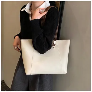 Detail of off-white tote bag with V-shaped stitching and dark brown straps on model