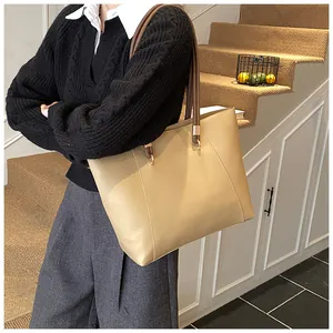 Detailed side view of a large brown faux leather tote bag worn on a woman's shoulder