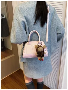 Nahaufnahme der rosa Leder-Baguette-Tasche mit Lukadi-Logo und süßem Bären-Anhänger
