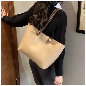 Detail view of beige tote bag with braided handles being carried by a model on shoulder