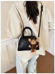 Detail der schwarzen Leder-Tote-Bag mit Silberlogo und süßem Teddybär-Anhänger