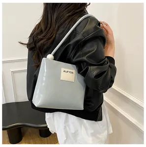 Dettaglio della borsa in pelle PU lucida azzurra con sfera decorativa bianca sulla tracolla