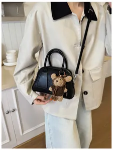 Details einer schwarzen Leder-Bagguette-Tasche mit süßem braunem Plüschbären-Anhänger