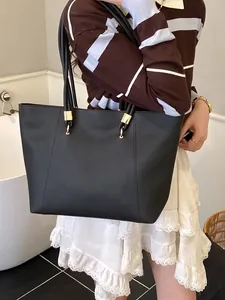 Minimalist black faux leather large tote bag with gold metal rings shown on a model