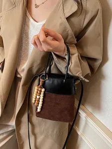 Chic two-tone bucket bag featuring retro patchwork design with elegant wooden bead charms