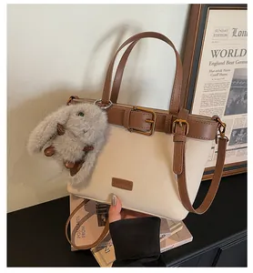 Gros plan du sac seau bicolore avec boucle dorée et accessoire charm lapin en peluche