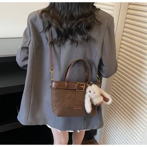 Détail du sac seau en daim marron avec ceinture en cuir et breloque lapin en peluche