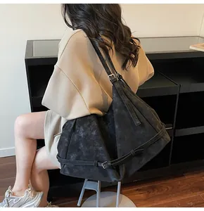 Detail view of large black tote bag with matte texture and decorative strap on shoulder