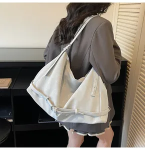 Side view of large grey matte leather tote bag worn over shoulder with casual blazer