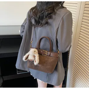Sac seau en daim marron avec garniture en cuir et charme lapin porté en bandoulière