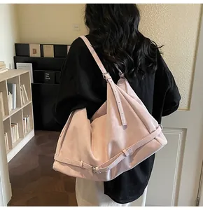 Detail of a large pale pink soft leather tote bag worn as a shoulder bag on a model