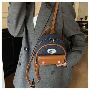 Vue détaillée du mini sac à dos en denim et cuir marron avec écusson d'ours et fermeture éclair