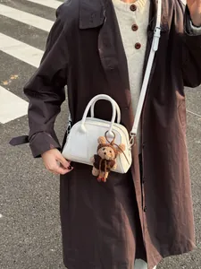 Weiße minimalistische Baguette-Tasche mit braunem Teddybär-Anhänger im Streetstyle-Look