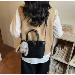 Détail du sac seau noir en cuir mat avec pendentif lapin en peluche et bandoulière