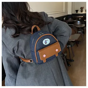 Vue arrière d'un mannequin portant le mini sac à dos en denim avec détails en cuir brun