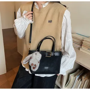 Détail du sac seau noir avec sangle à boucle et breloque lapin en peluche sur modèle