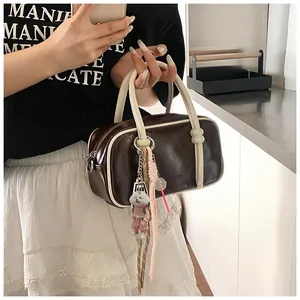 Détail du sac bowling marron avec anses blanches, boucle turquoise et charm de petit chien