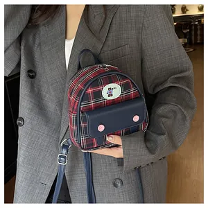Detailed shot of a mini plaid backpack with cartoon bear patch and navy leather pocket flap